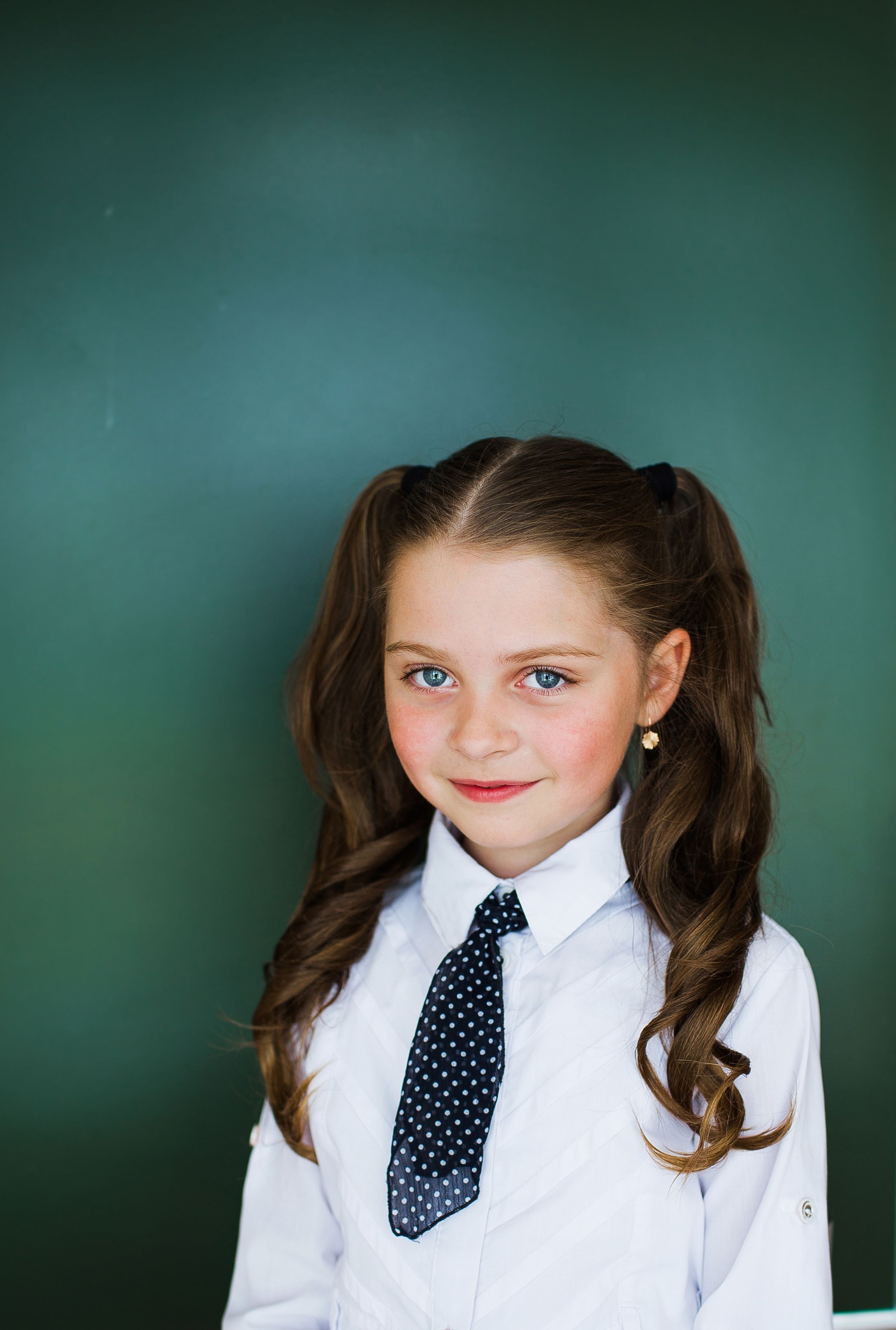 Junge Schülerin in der Nähe der Tafel in einem weißen Hemd und Krawatte